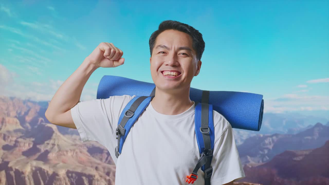 Close Up Of Asian Male Hiker With Mountaineering Backpack Smiling And Flexing His Bicep While Traveling At The Top Of Mountain
