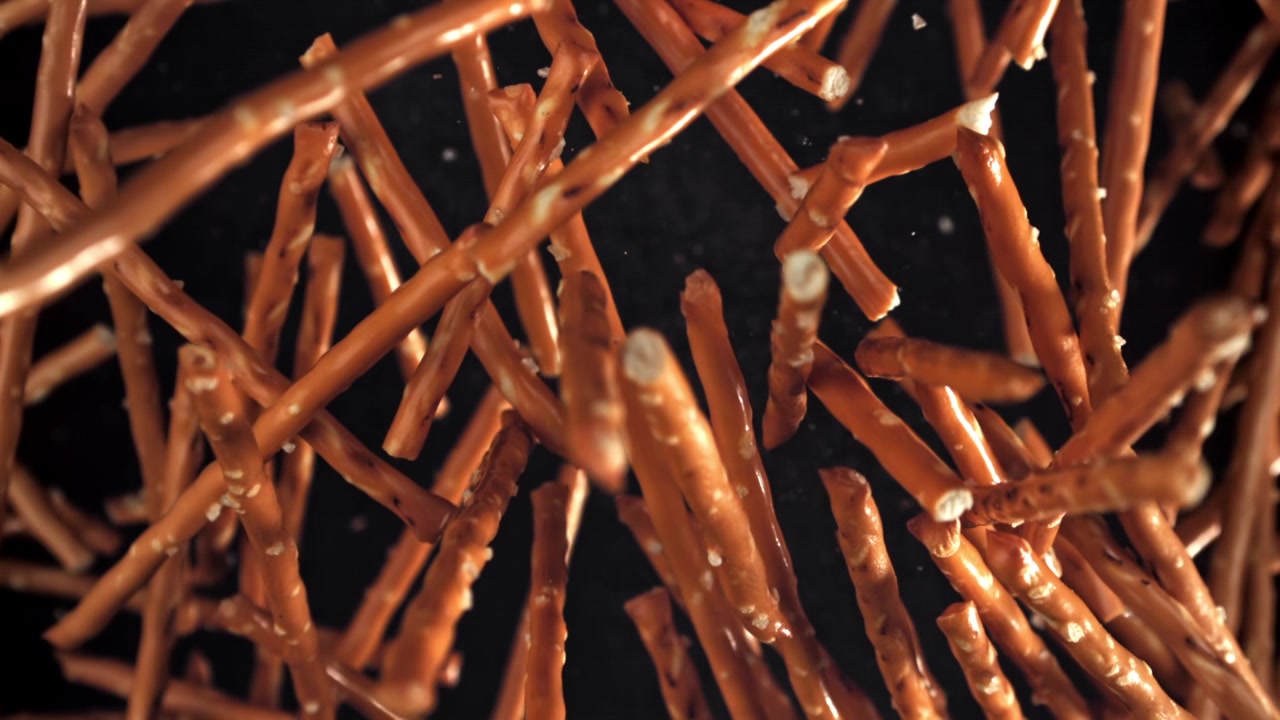 Bastoncini di pretzel che cadono al rallentatore su uno sfondo nero.