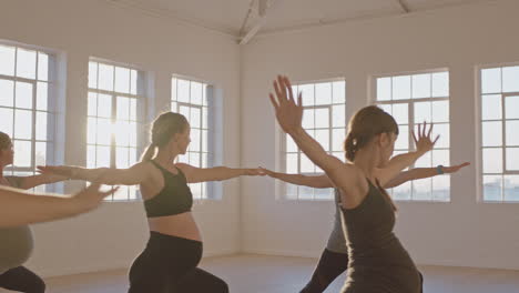 Instructor-De-Clase-De-Yoga-Enseñando-A-Mujeres-Embarazadas-A-Ejercer-Un-Estilo-De-Vida-Saludable-Practicando-Pose-De-Guerrero-Disfrutando-De-Un-Entrenamiento-Físico-En-Grupo-En-El-Estudio-Al-Amanecer.