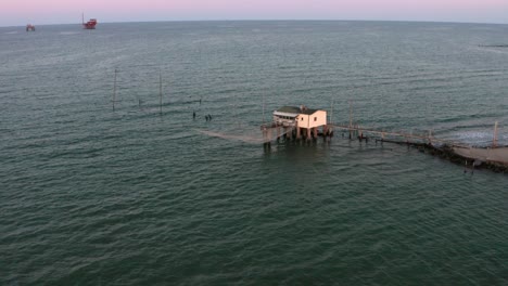 Aerial-shot-of-the-valleys-near-Ravenna-where-the-river-flows-into-the-sea-with-the-typical-fishermen's-huts-at-sunset