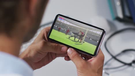 Compuesto-De-Un-Médico-Masculino-Viendo-Un-Partido-De-Rugby-En-Un-Teléfono-Inteligente