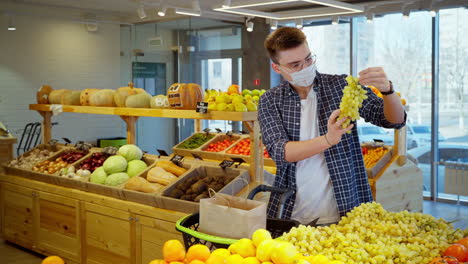 hombre comprando uvas en una tienda de comestibles
