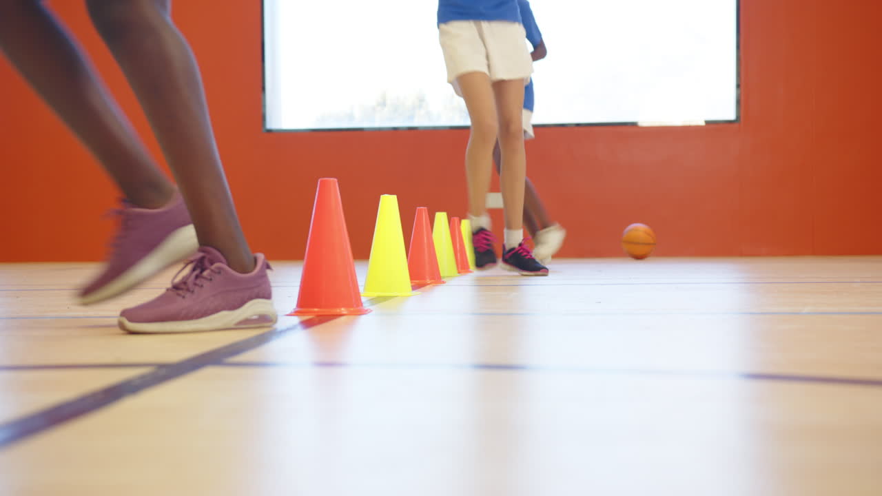 Running in gym, kids practicing agility drills with cones in school