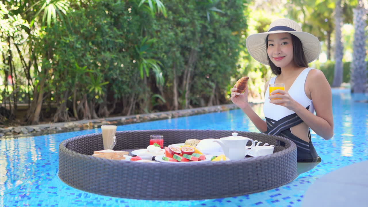 A young woman holding a glass of orange juice in one hand spins the floating food platter looking for just the right breakfast food