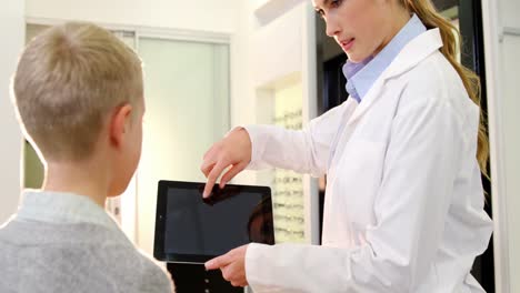 Female-optometrist-assisting-young-patient-on-digital-tablet