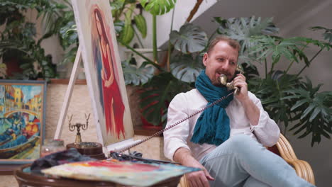 man artist with beard engages with vintage phone. artist sets down palette for important call blurring boundaries between personal and creative pursuits