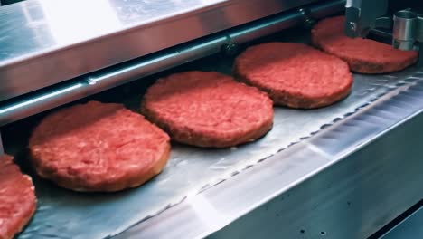 burger patties on a conveyor belt