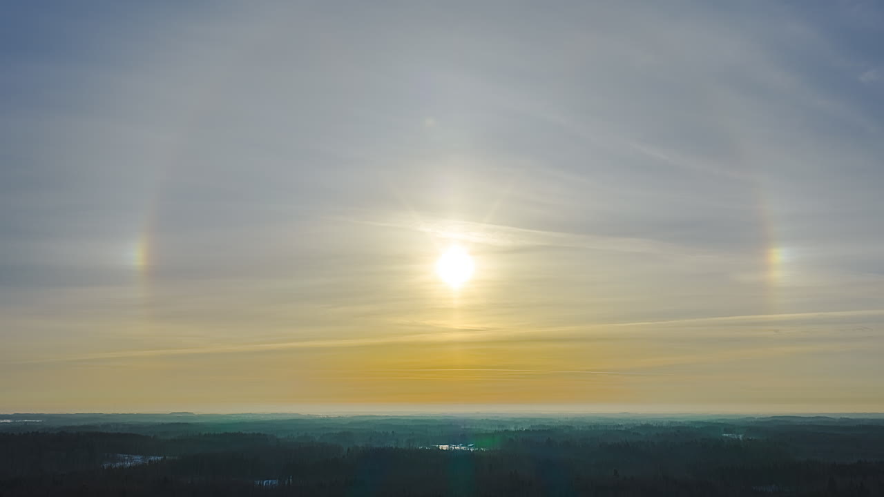 Rare optical sun dog parhelion effect with glowing light halo over scenic landscape at golden hour during colorful sunset