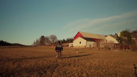 Rear-Of-A-Man-Pushing-Wheelbarrow-On-A-Sunset-Meadows-Near-Rural-Village