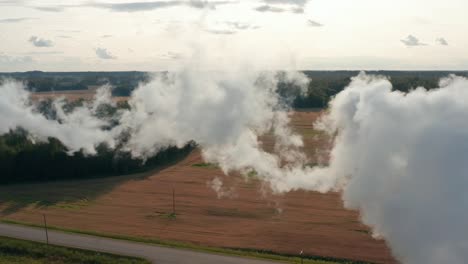 Aerial-drone-shot-of-a-factory-chimney-spewing-fumes-into-atmosphere-in-rural-area