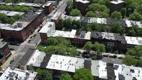 aerial drone view of brooklyn in spring, featuring lush green trees, classic brownstones, and quiet streets. ideal for real estate, cityscape, and seasonal neighborhood imagery.