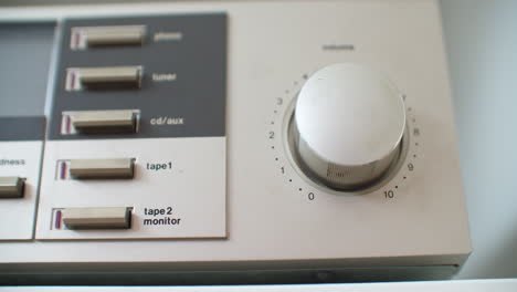 Close-up-shot-of-adjusting-the-volume-knob-of-an-old-vintage-silver-stereo-system