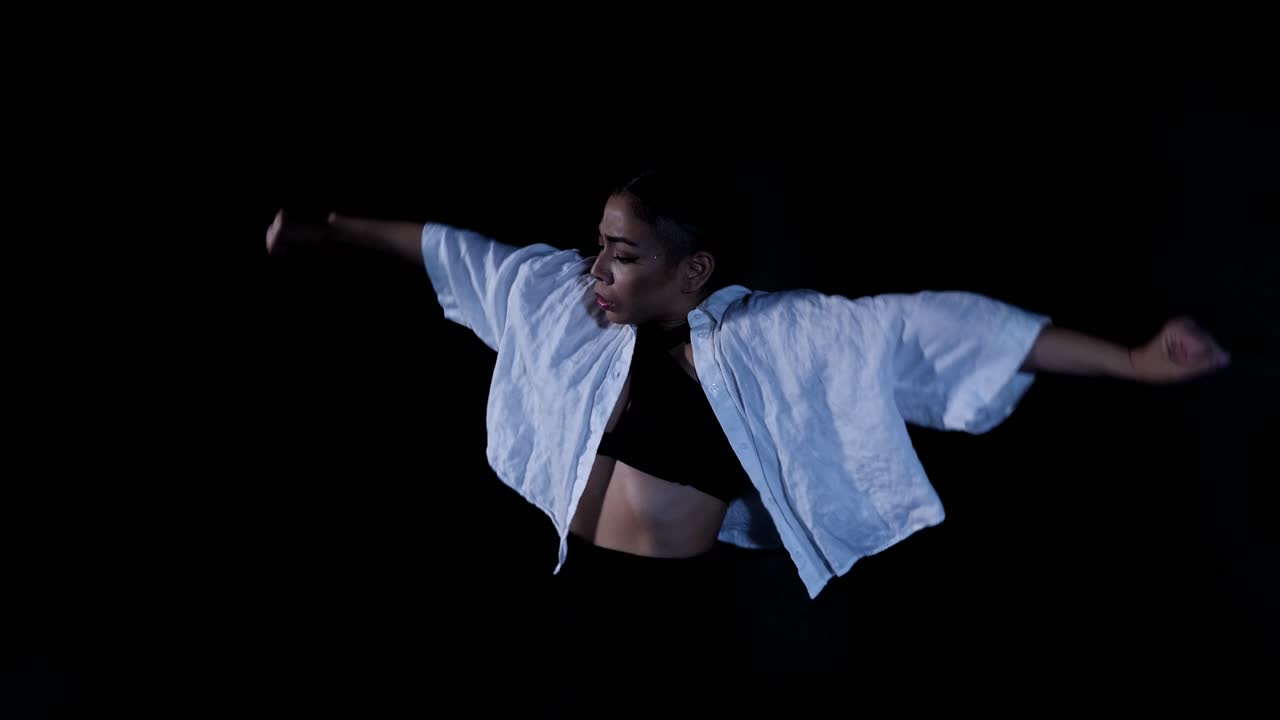 Young Latina Woman Dancing Whacking in Slow Dramatic Emotional Release with White Top on Black Background
