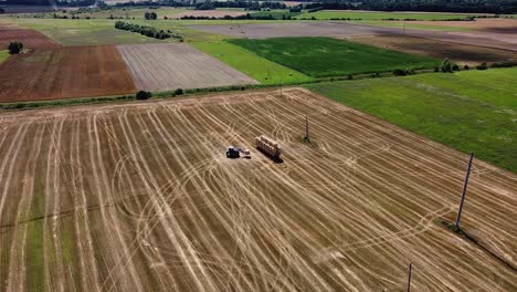 arial drone shot of farmer collecting hay rolls from the field