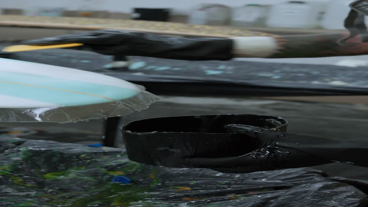 익명의 사람이 서프보드에 스크레이퍼를 붙이고 있습니다.