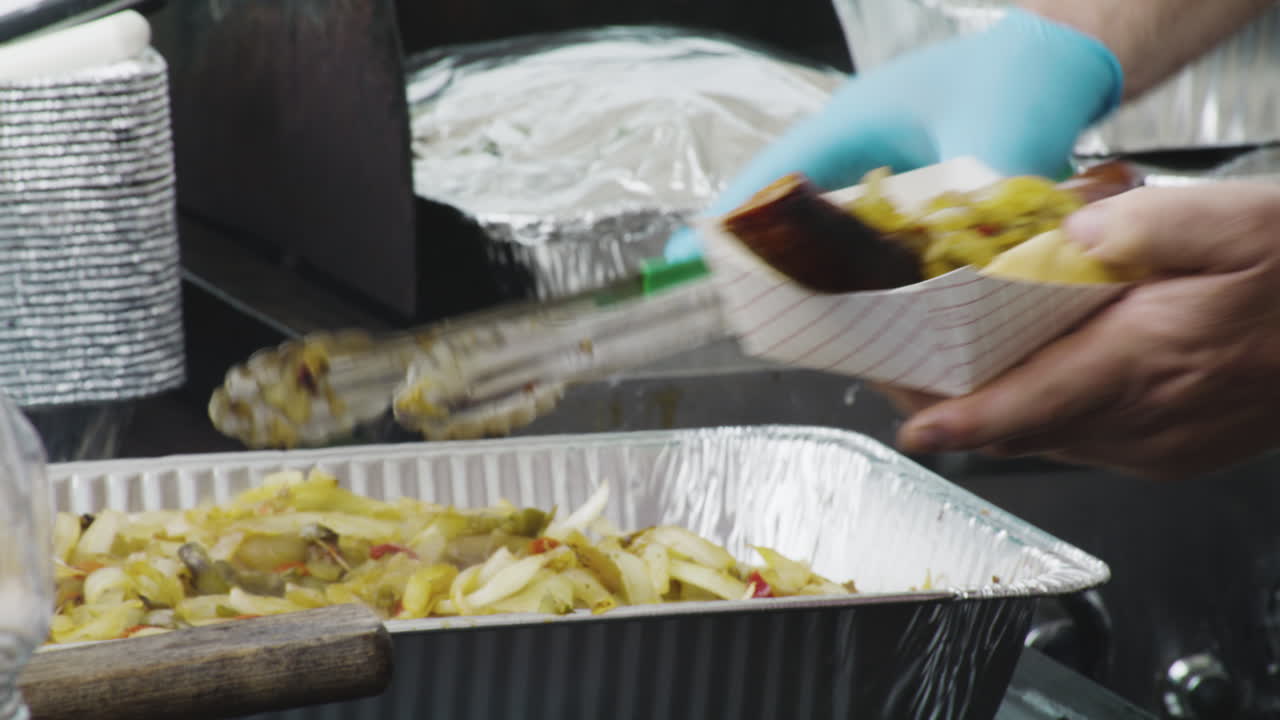 vendedor ambulante de comida en el festival agrega una porción de cebollas a un hot dog bratwurst - dogwood siloam springs arkansas