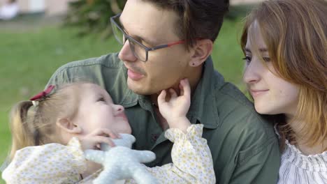 una joven familia feliz, padre y madre pasando tiempo con su alegre hija en el parque de la ciudad