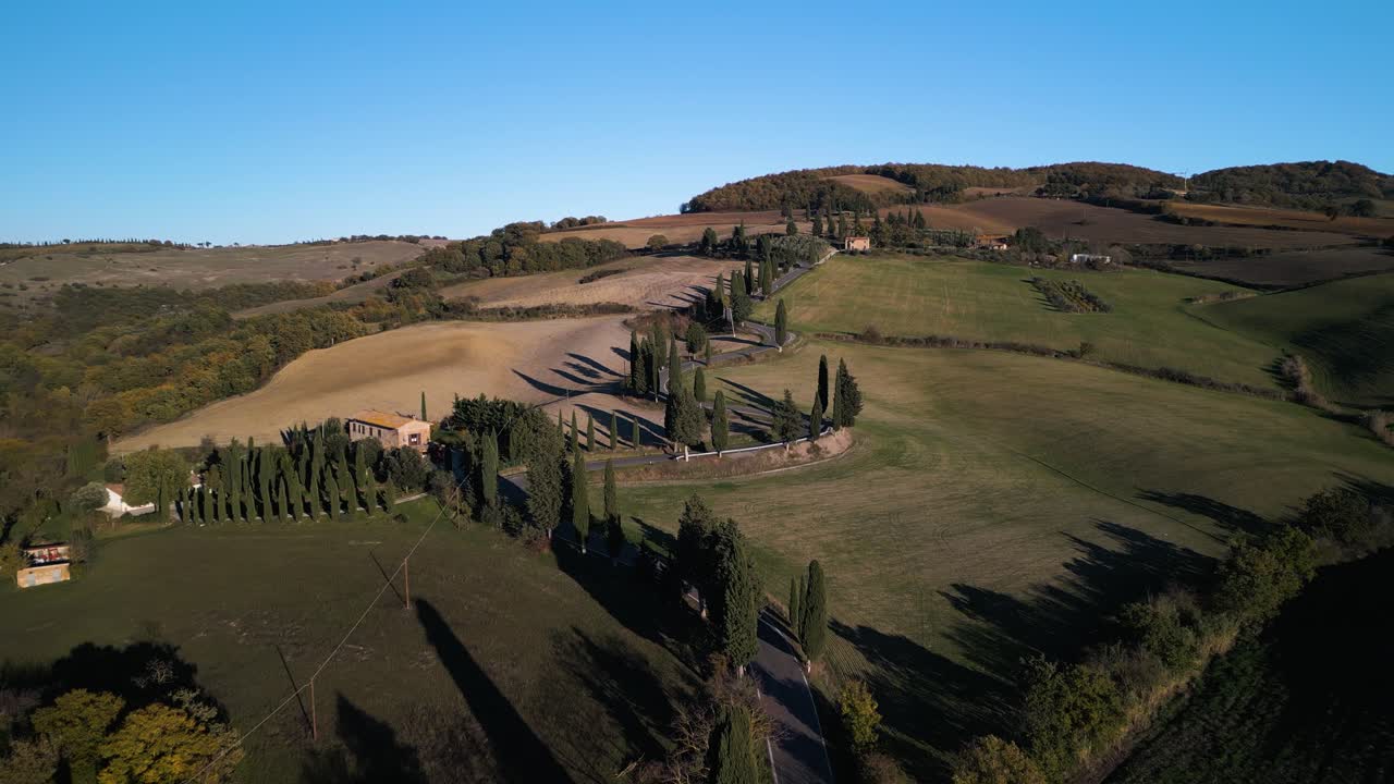 사이프러스 나무가 있는 은 은 도로가 정오에 토스카니아의 언덕을 따라 굴러 올라갑니다.