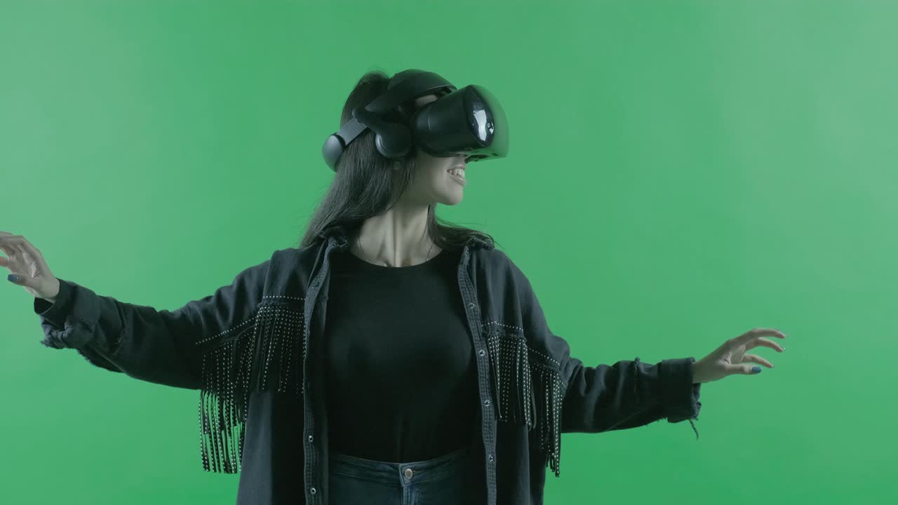 la giovane donna si guarda intorno e si chiede quanto sia sorprendente l'auricolare vr. casco di realtà virtuale sullo sfondo verde. chiave croma