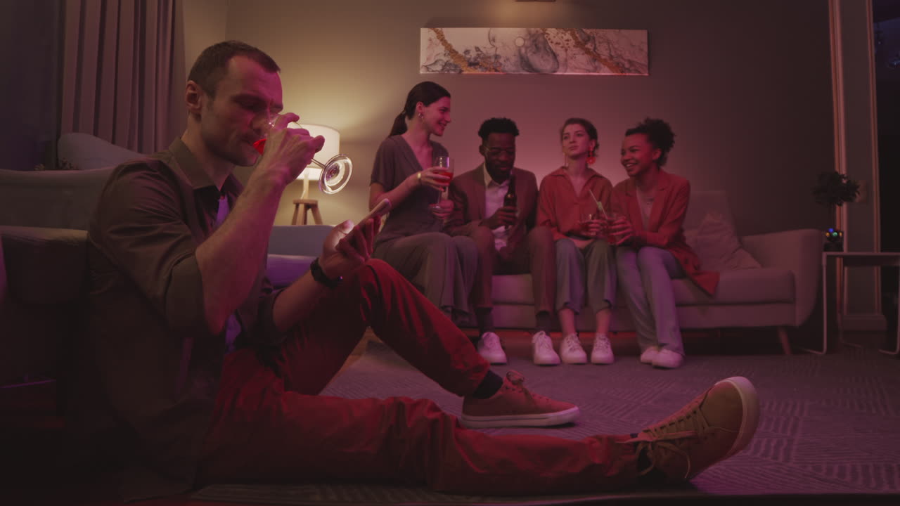 Man Scrolling on Phone during Friends Home Party