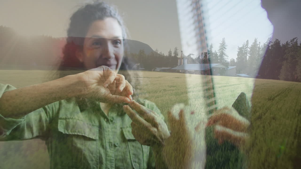 Woman making expressive hand gestures inside near window, overlaying agriculture field with silos