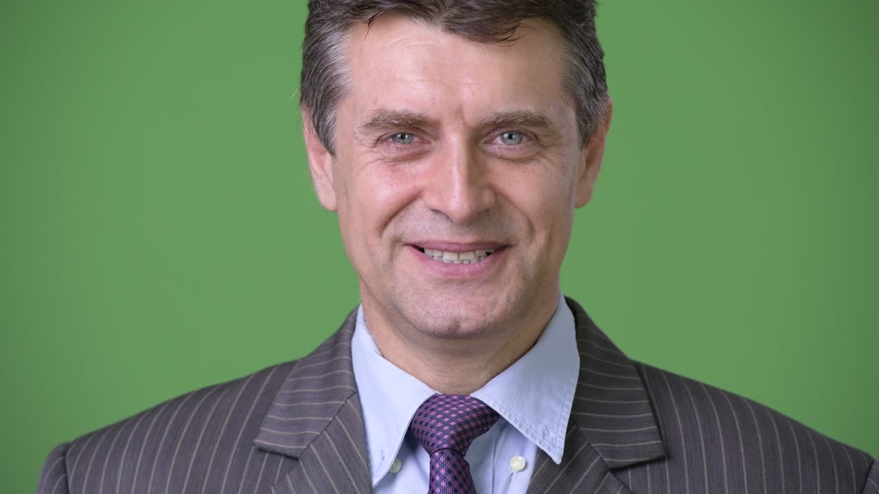 hombre de negocios maduro y guapo contra un fondo verde