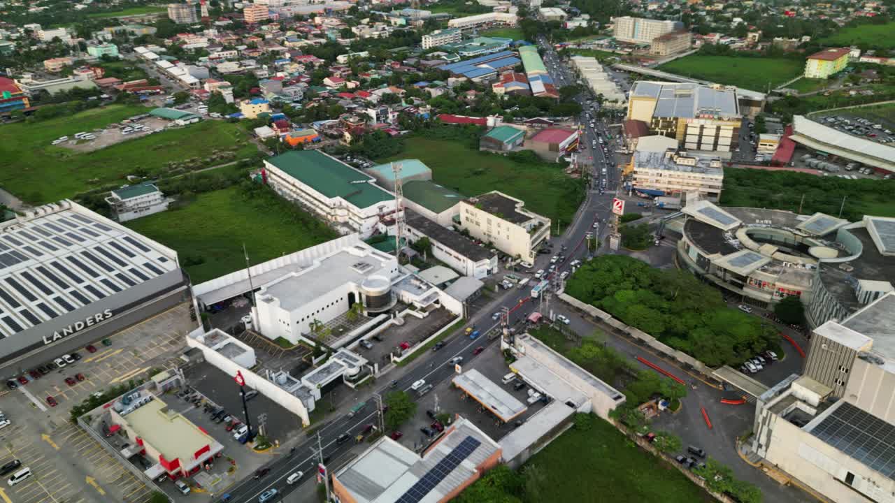 Aerial pullback revealing busy streets, commercial buildings, and lush green spaces across Naga City, Camarines Sur, Bicol, Philippines