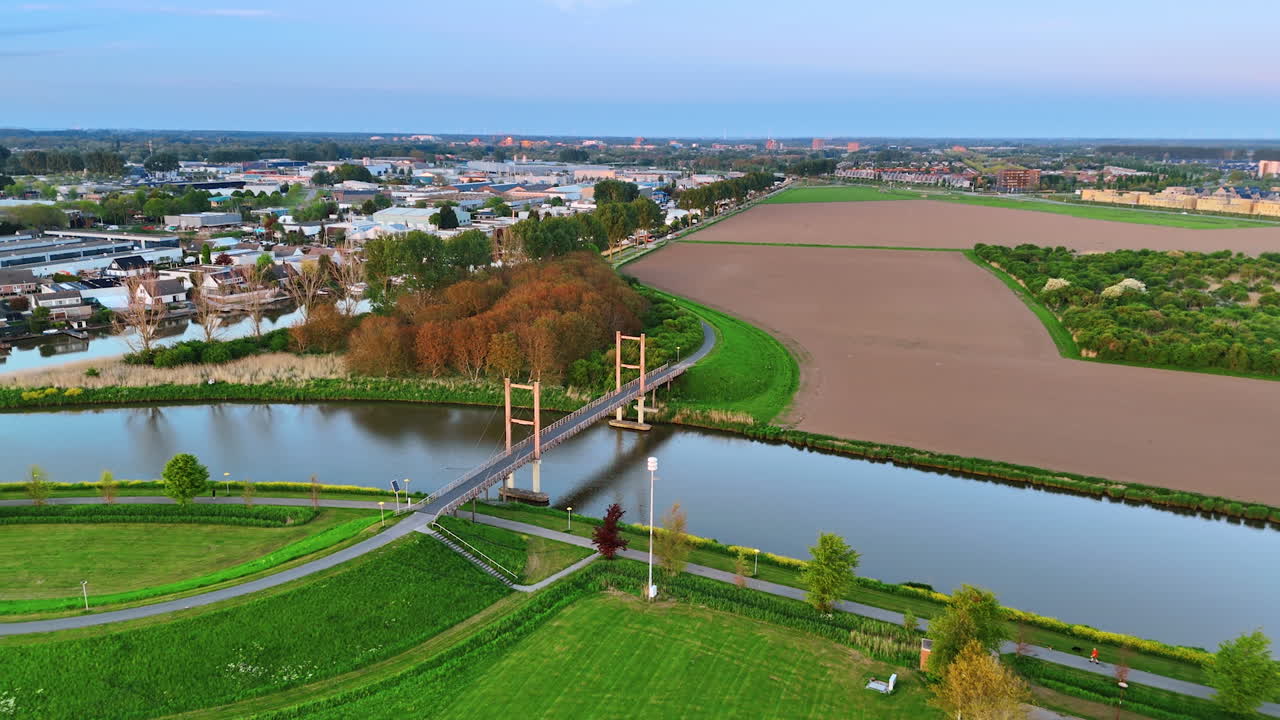 Approaching a bridge over the canal in Lelystad, the Netherlands. Drone footage over the cityscape at sunset time.