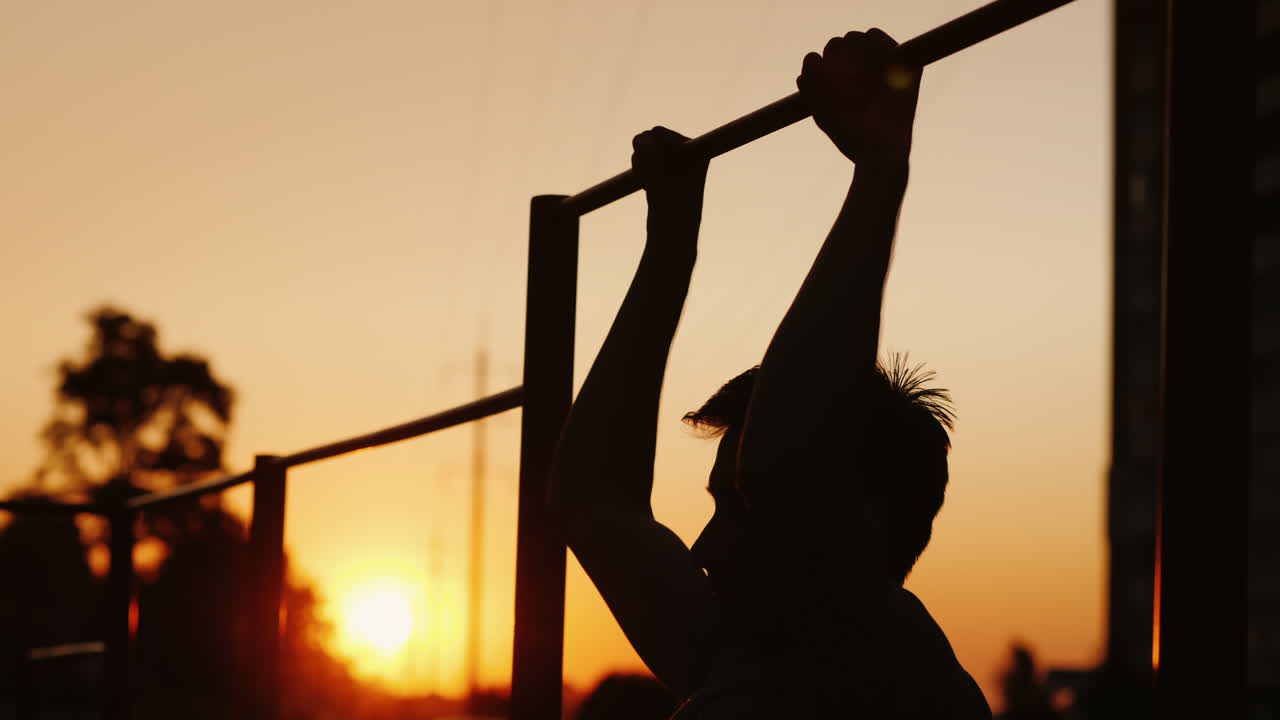 10대 소년은 마당 거리 훈련과 젊은이들 사이의 스포츠에서 수평 막대에 몸을 끌어당긴다