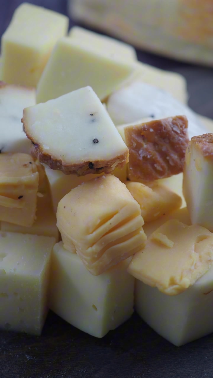 Primer plano de cubos de queso variados sobre una tabla oscura