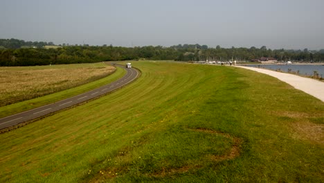 Looking-up-Carsington-water-dam,-with-the-dam-road-to-the-left-frame-with-traffic