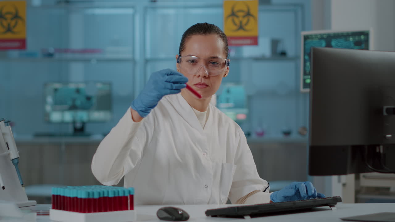 Woman scientist analyzing liquid in test tube and using computer