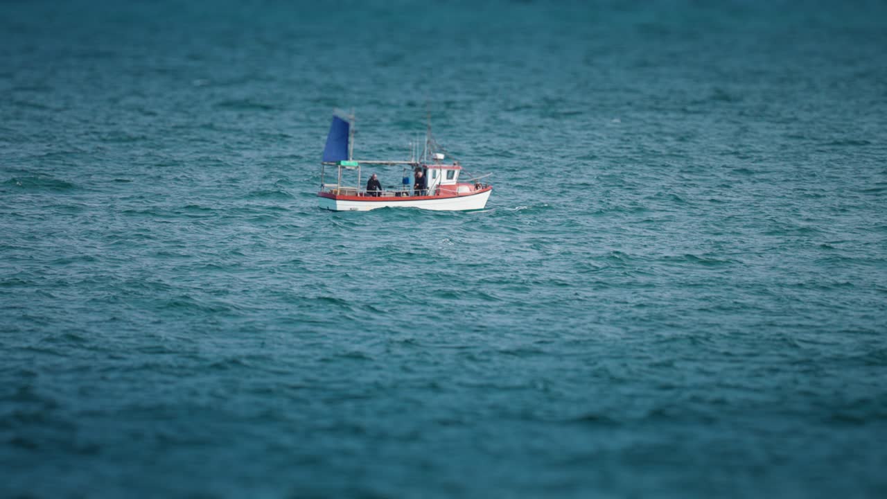 Una barca da pesca solitaria con un pescatore a bordo che cavalca le onde nel mare agitato del nord