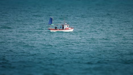 a lone fishing boat with one fisherman aboard riding the waves in the rough northern sea