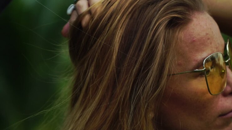 Primo piano di una bella ragazza caucasica con occhiali da sole che si tocca i lunghi capelli biondi