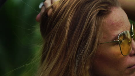 Close-up-of-a-beautiful-Caucasian-girl-with-sunglasses-touching-her-long-blond-hair