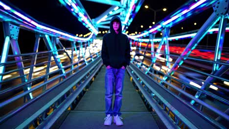 teenager standing on a pedestrian bridge with neon lights and light trails from passing cars at night, creating a futuristic and cyberpunk atmosphere