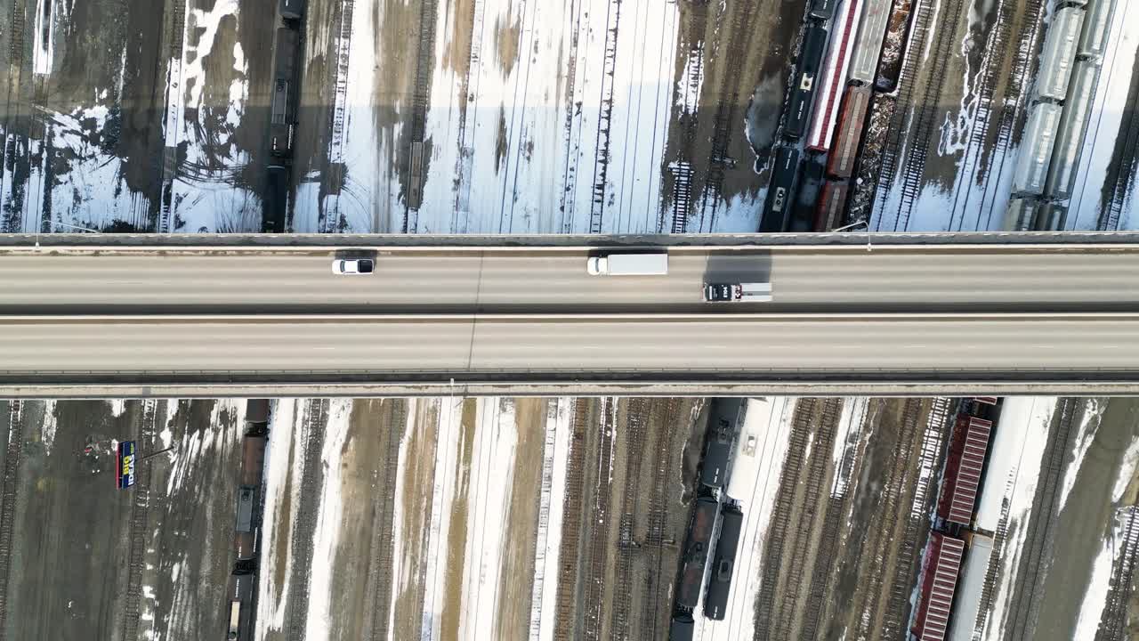 Top down timelapse drone shot of cars crossing a bridge over a rail yard