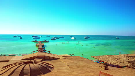 Time-lapse-shot-of-a-touristic-beach-with-people-in-the-water-and-yachts-on-the-turquoise-water