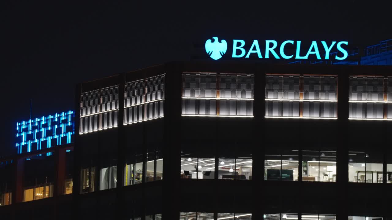 At night, Barclays logo glows, beacon of finance where the city flows