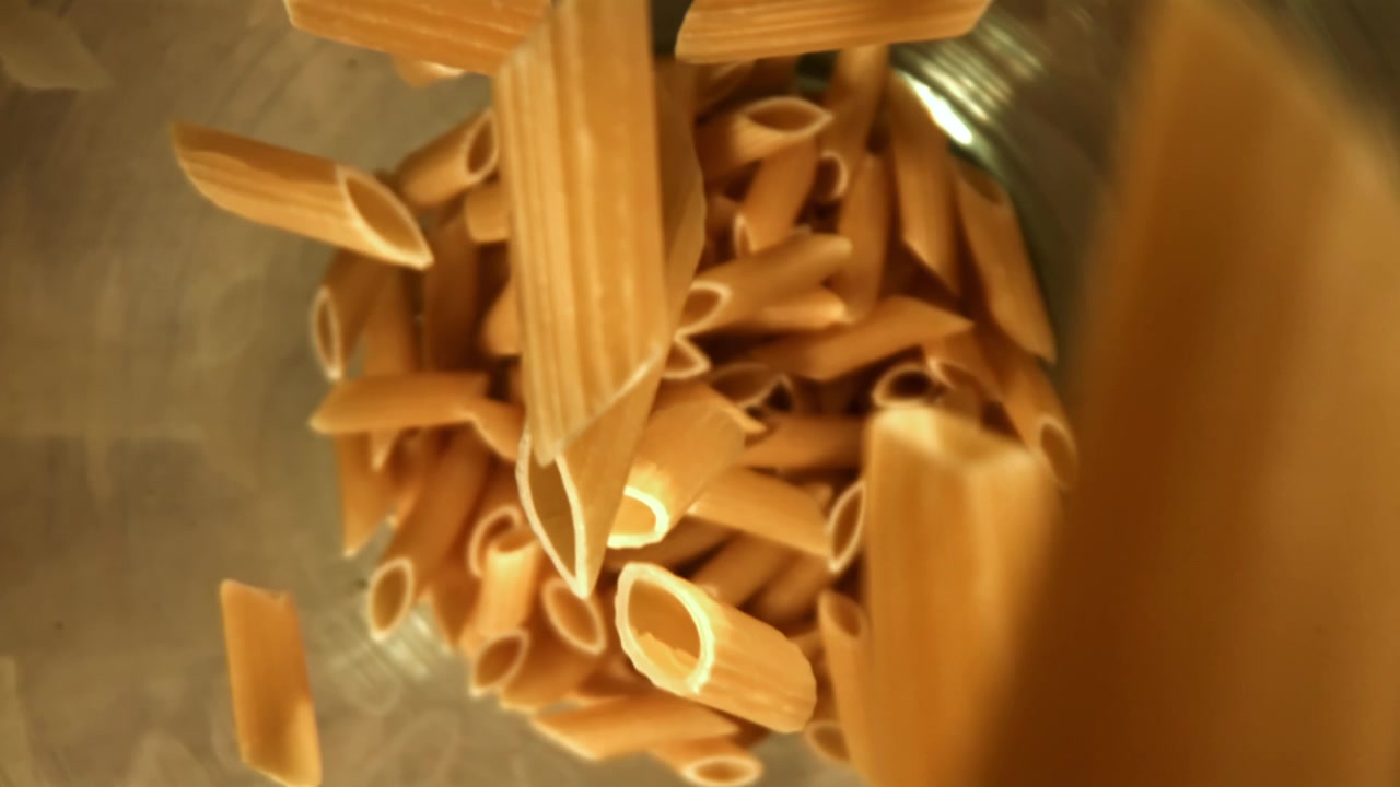 Pasta penne che cade in una pentola al rallentatore