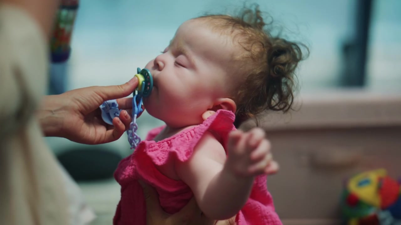 Close up of a baby receiving a pacifier, showing a tender caregiving moment with shallow depth of field