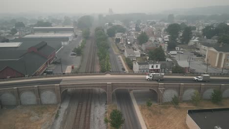aerial view of cars passing over railroad bridge in thick smoke and smog