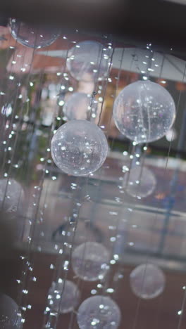 primer plano de esferas translúcidas festivas suspendidas con luces de cuerda brillantes, creando un ambiente navideño mágico con reflejos de luz borrosos y silbidos ocasionales en el fondo