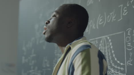 man studying documents and explaining concepts on a blackboard in a classroom