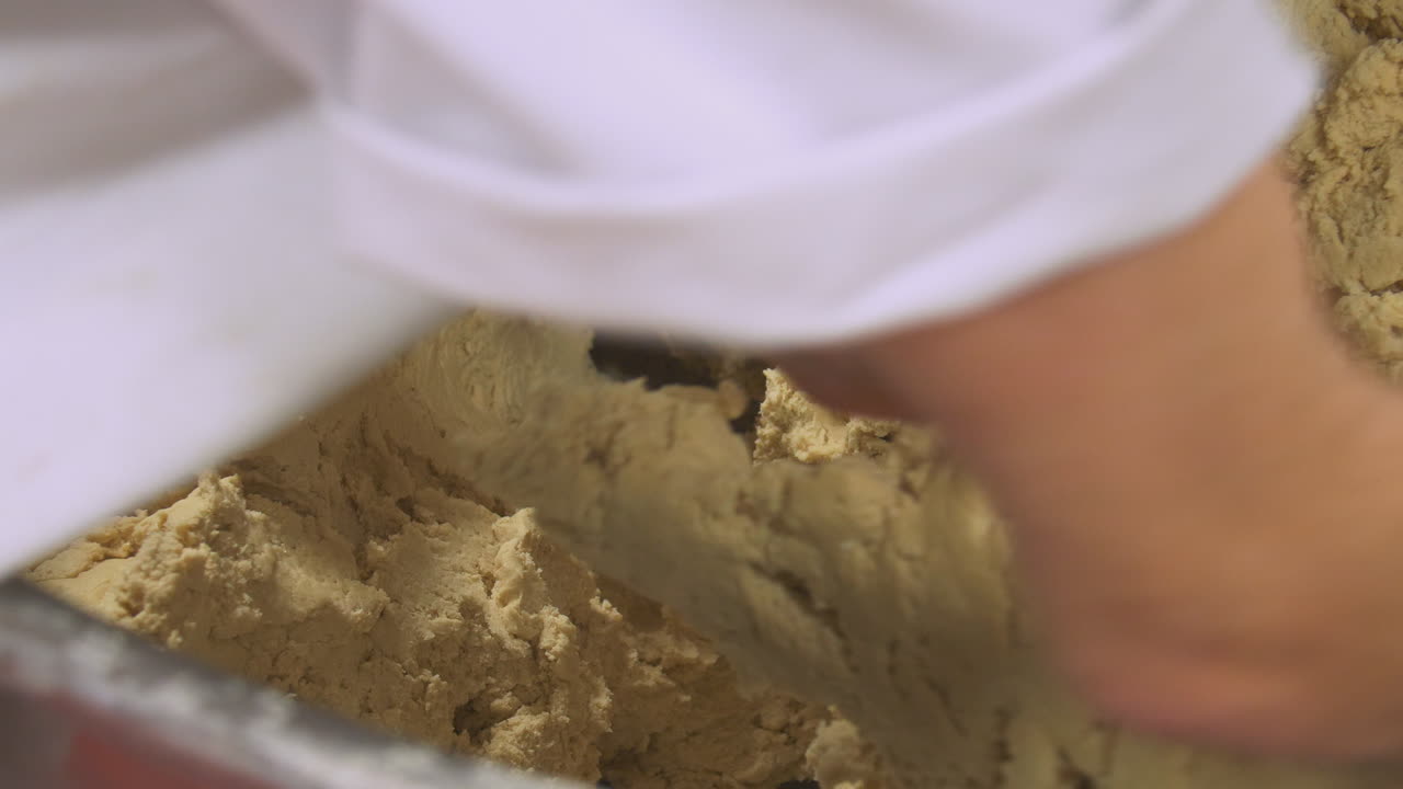 Workers pick up lumps of dough ready for production of cakes in a factory
