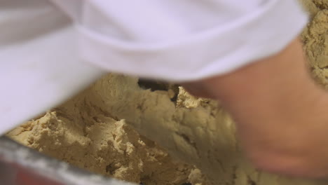 workers pick up lumps of dough ready for production of cakes in a factory