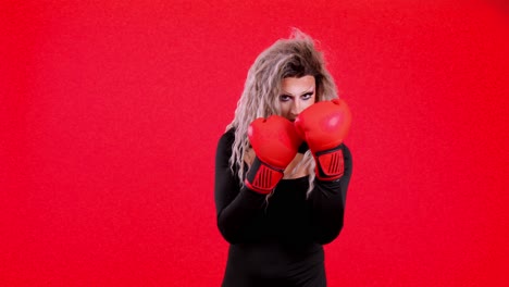 drag performer posing with boxing gloves on red background