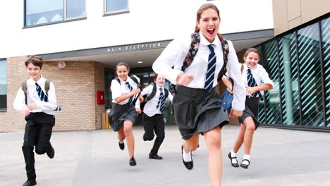 Gruppe-Von-Gymnasiasten-In-Uniform,-Die-Am-Ende-Des-Unterrichts-Aus-Schulgebäuden-In-Richtung-Kamera-Läuft