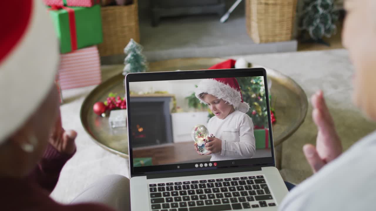 amigas mayores diversas usando computadora portátil para una videollamada de navidad con un chico caucásico en la pantalla